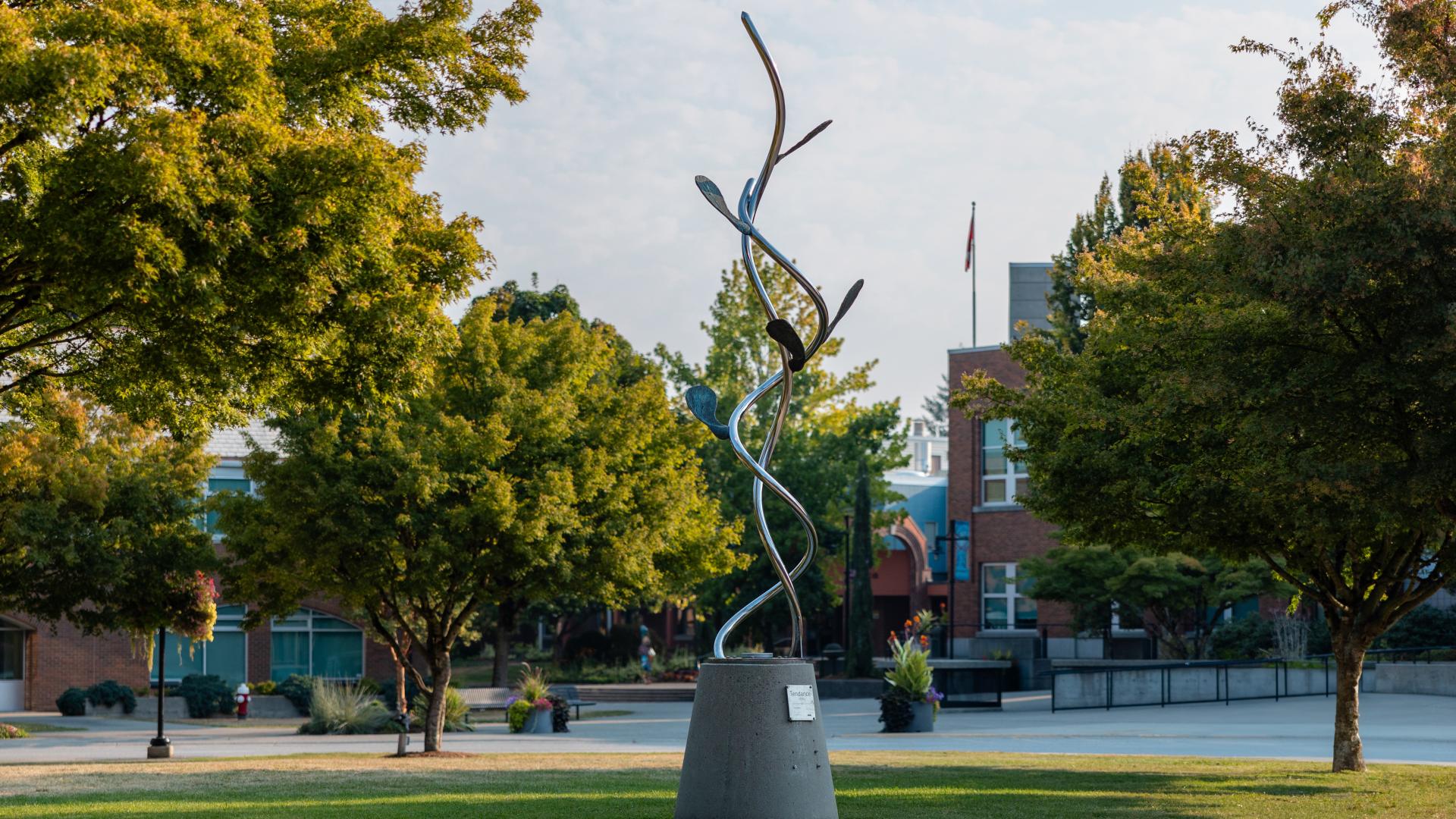 A silver statue of vines and leaves stands out against lush trees in Memorial Peace Park.